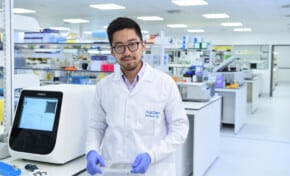 dr Michael Chen standing with eProtein Discovery holding smart cartridge in the lab